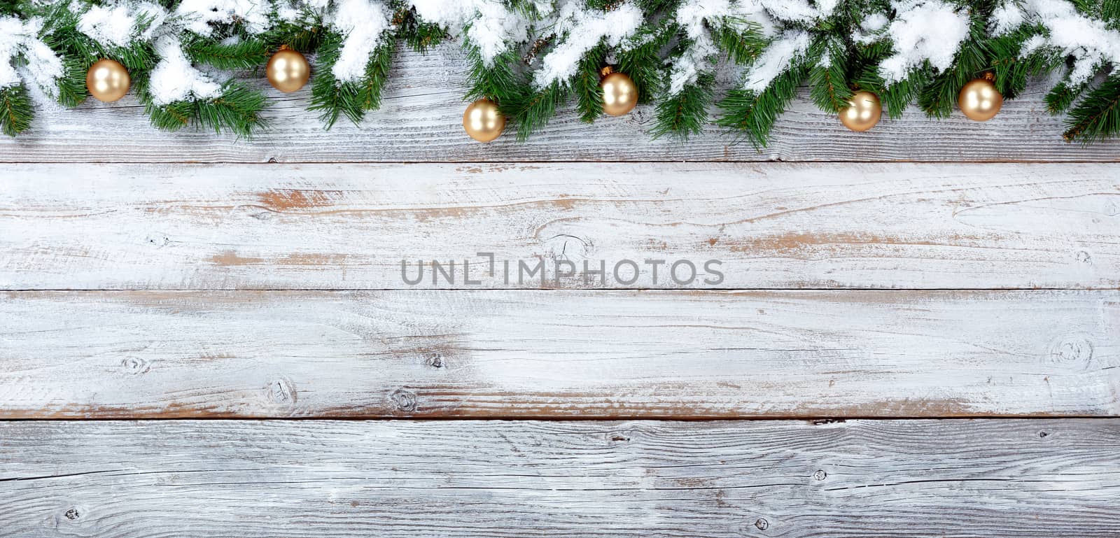 Top border of snow covered Christmas evergreen branches and Golden ornaments on white vintage wood