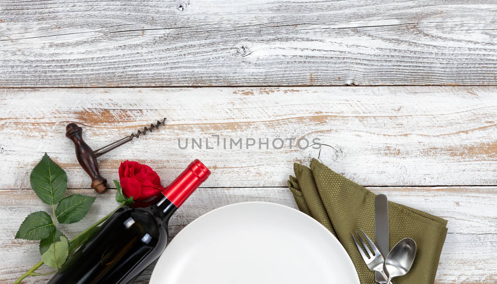 Top view dinner plate setting with red wine and rose