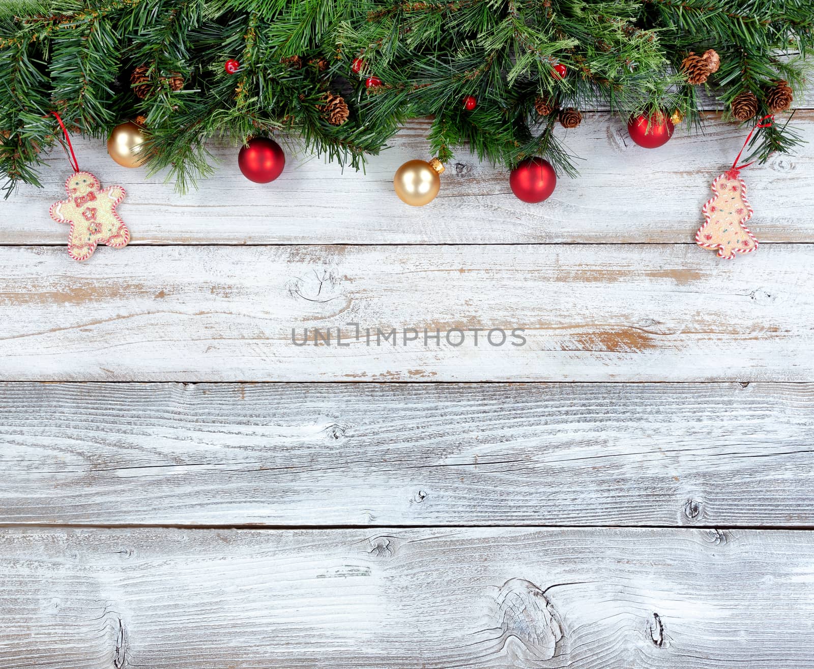 Top border of Christmas evergreen branches with other holiday decorations on white rustic wood