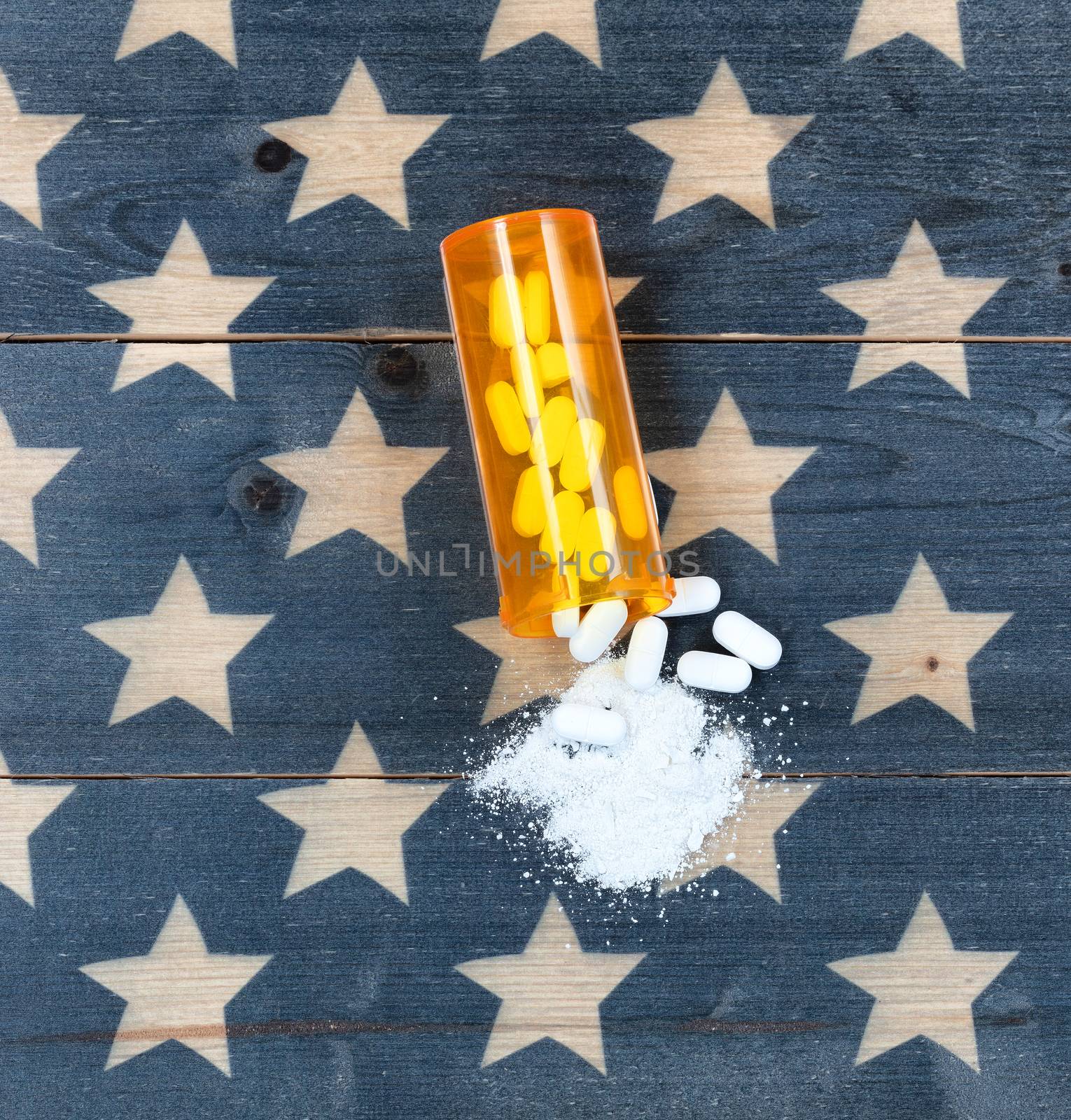 Overhead view of prescription bottle filled with generic opioid pain killer tablets on rustic USA flag in background for drug addiction concept in America  