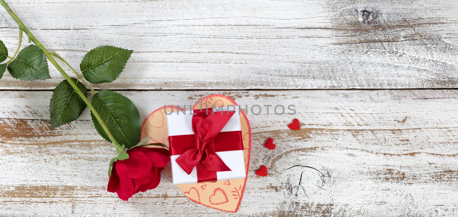 Valentines gift box on top of card with rose and heart shapes in overhead view layout