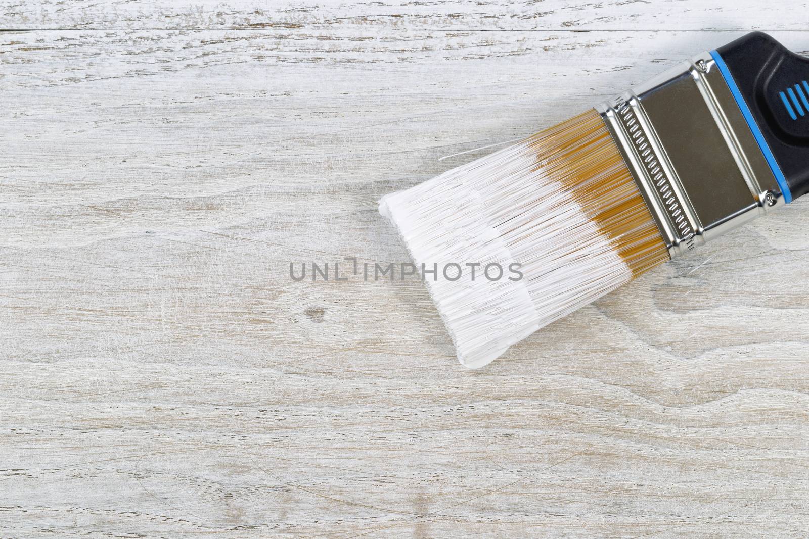 Wet paint brush ready to apply paint on old boards  by tab1962