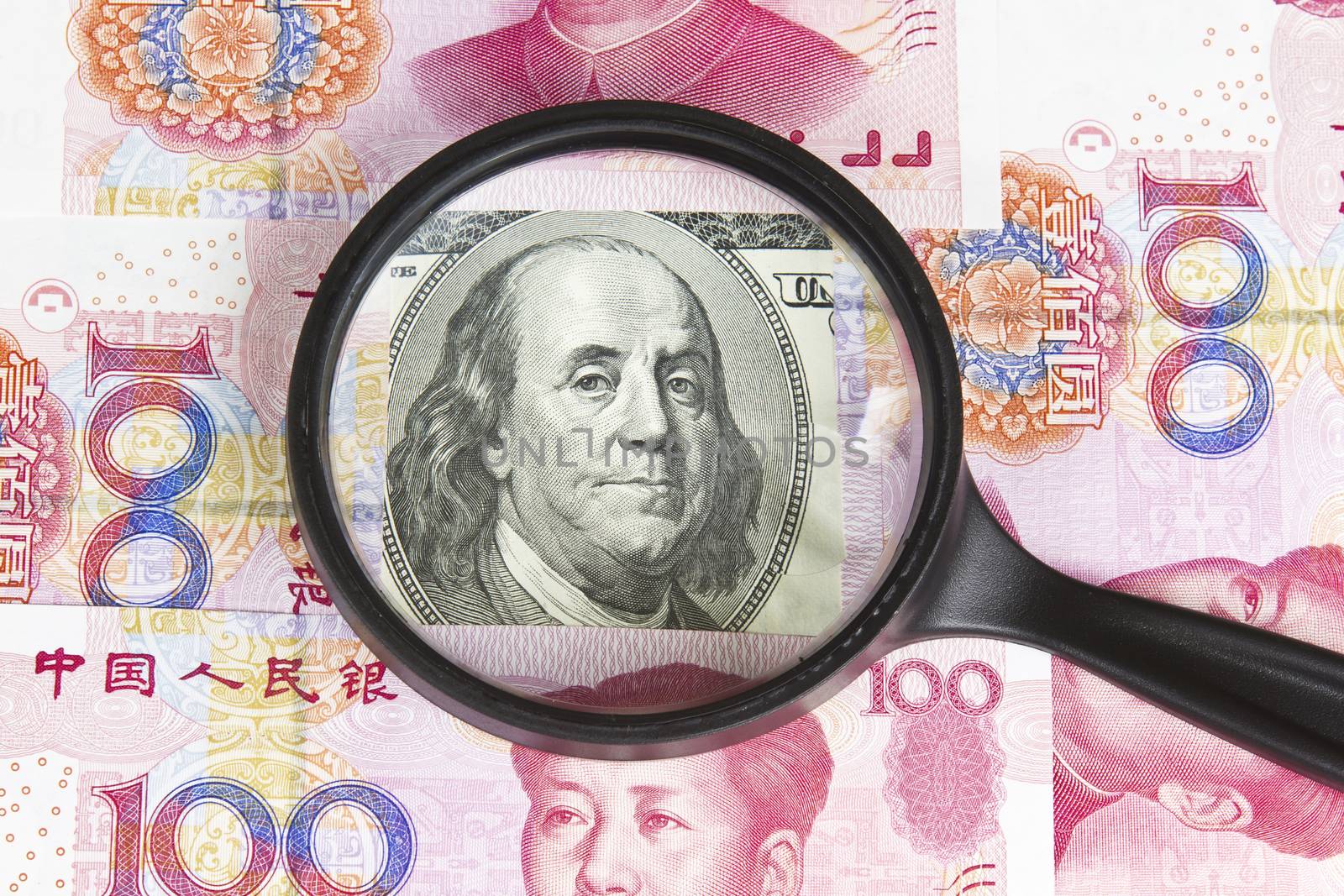 United States paper currency under magnifying glass with Chinese currency as background