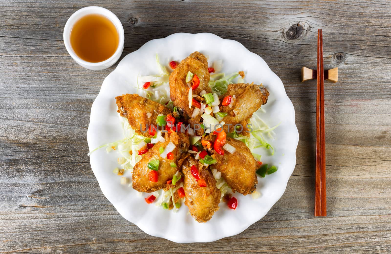 Asian style chicken wings with tea in white plate on rustic wood by tab1962