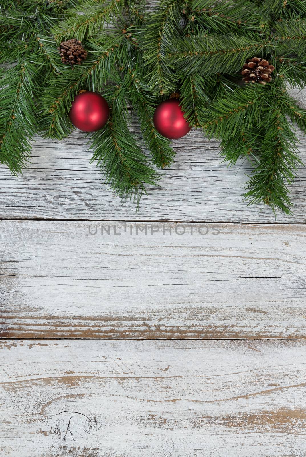 Traditional Christmas evergreen branches with red ball ornaments decorations on rustic knotty wood in flat lay format
