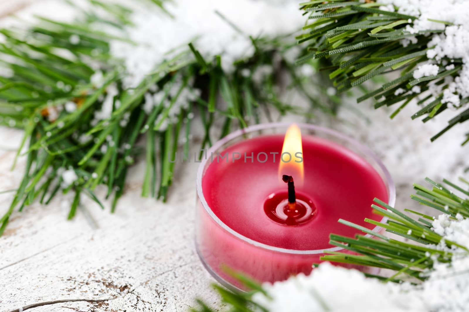 Glowing candle for Christmas holiday with evergreen and snow in  by tab1962