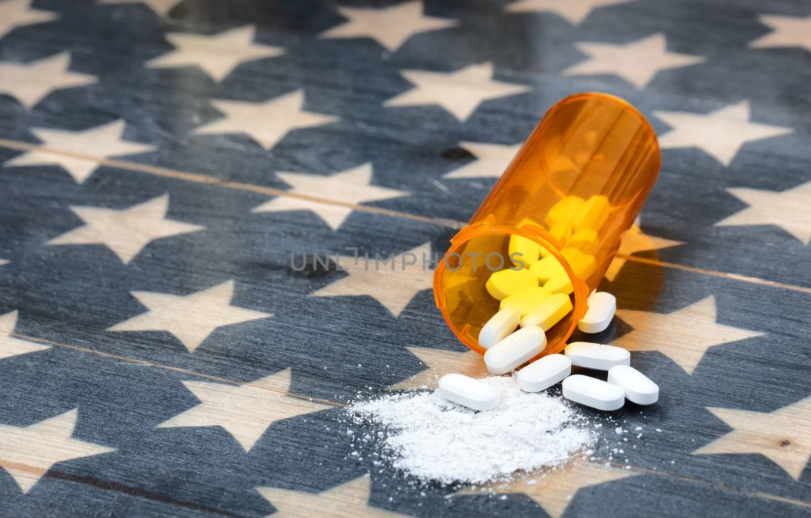 Front view of prescription bottle filled with generic opioid pain killer tablets on rustic USA flag in background for drug addiction concept in America  