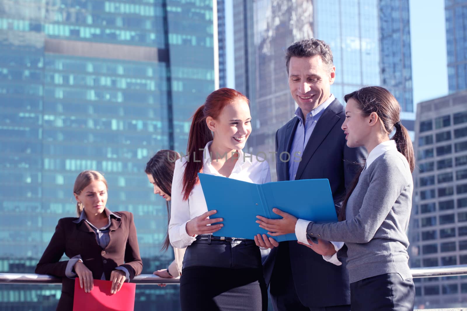 Business people meeting outdoors reding documents over skyscrapers background