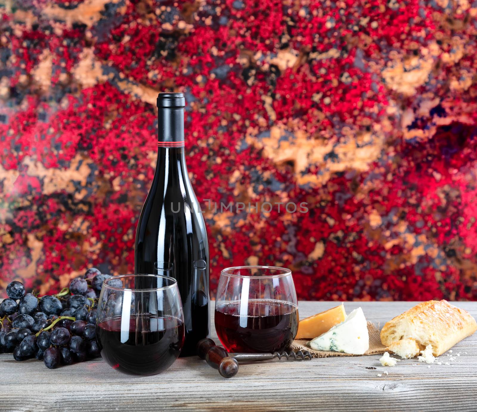 Red wine with cheese and bread on rustic wooden table