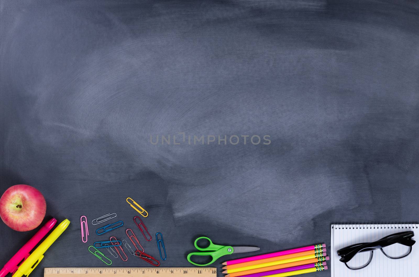 Back to school concept with student supplies on lower part of chalkboard.