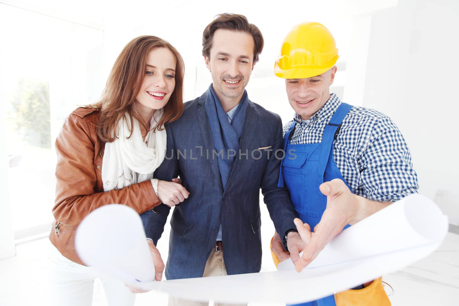 Foreman showing house design construction plan to a happy young couple new house real estate concept