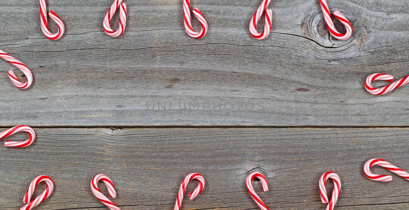 Top view close up of candy canes forming border on rustic wooden boards 