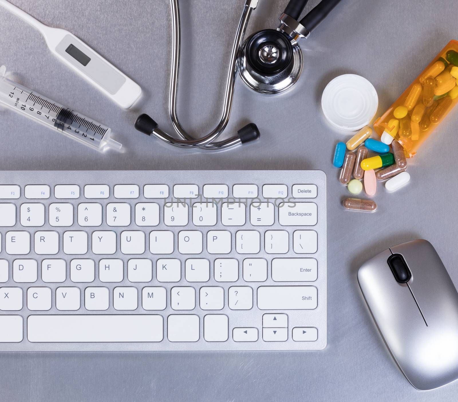 Medical doctor table desk with computer keyboard, stethoscope, thermometer, medicine, mouse, and syringe. Flay layout.