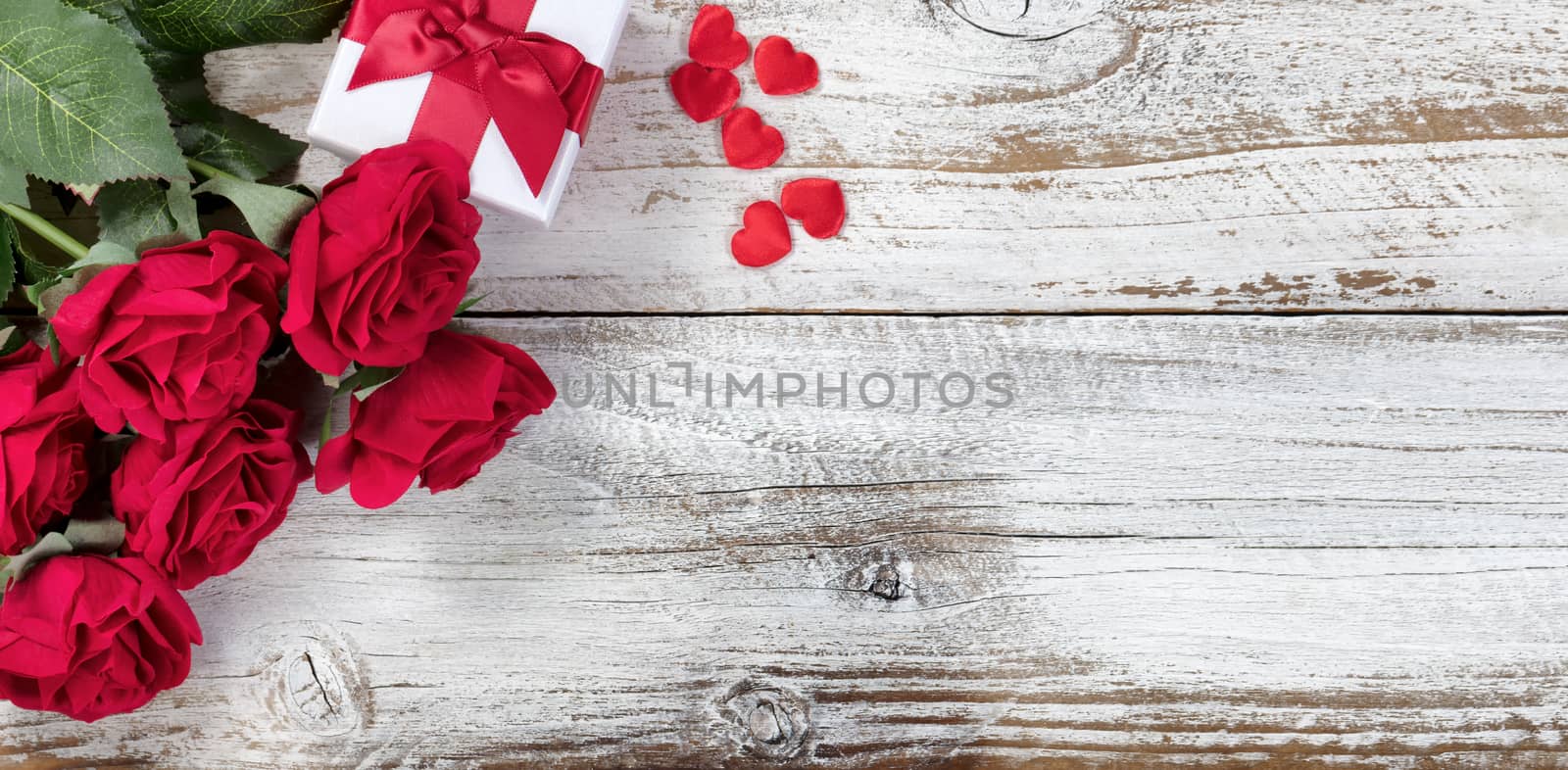 Gift box with red roses and hearts on rustic wood in flat lay view