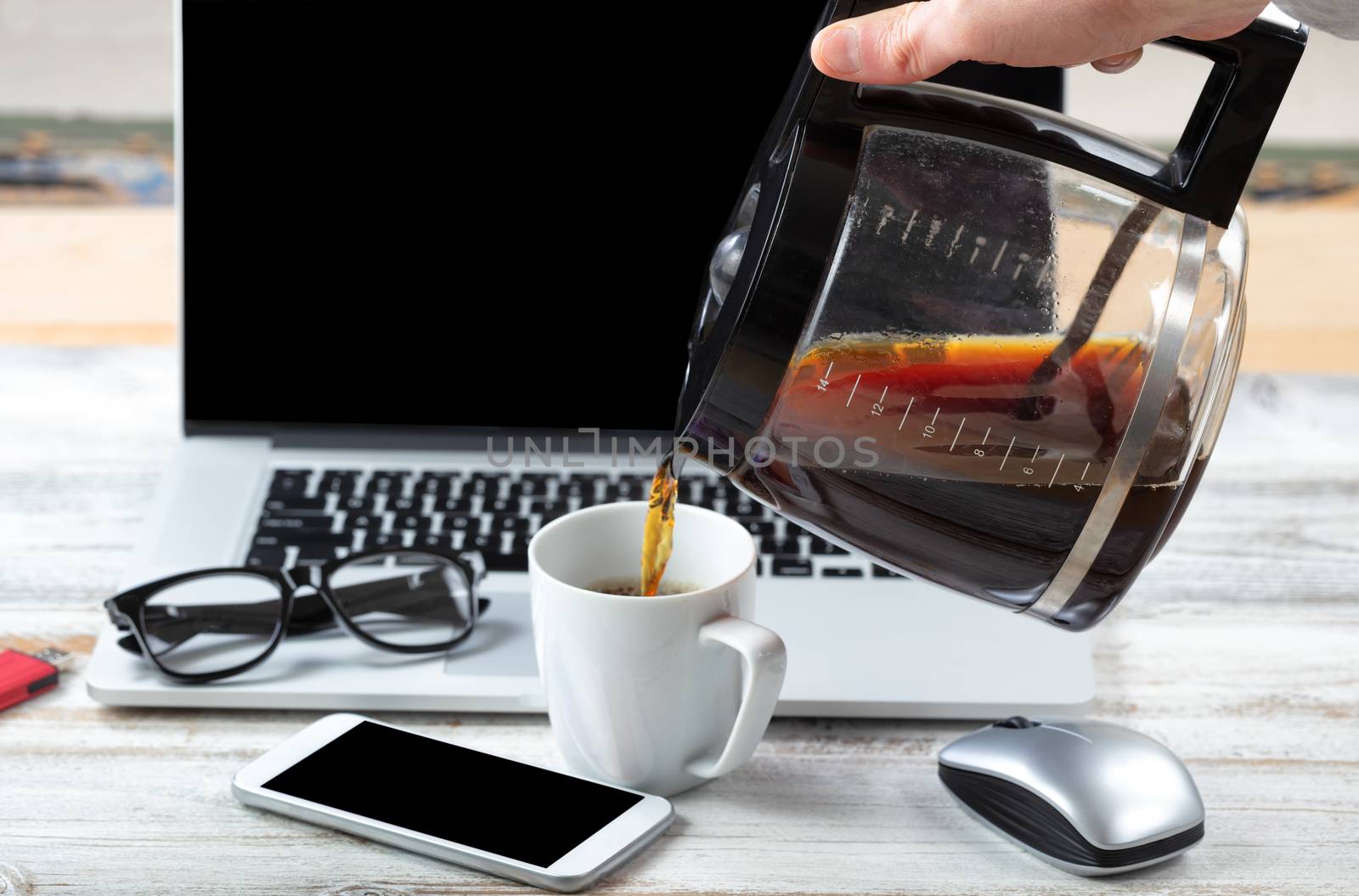 Close up of male hand pouring fresh coffee with workstation technology in background for business or education use 