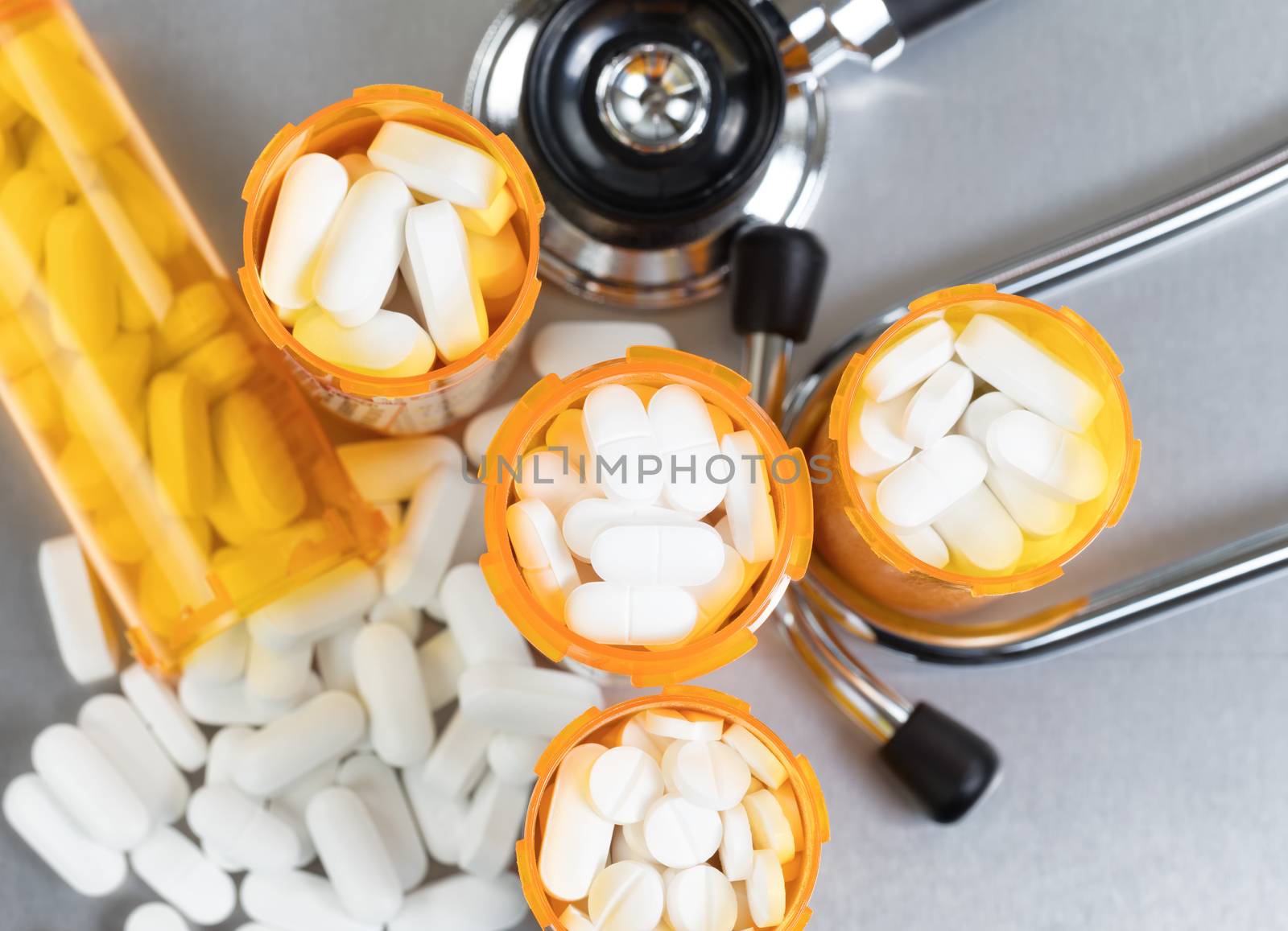 Top view of full prescription bottles with stethoscope and pills on stainless steel background 