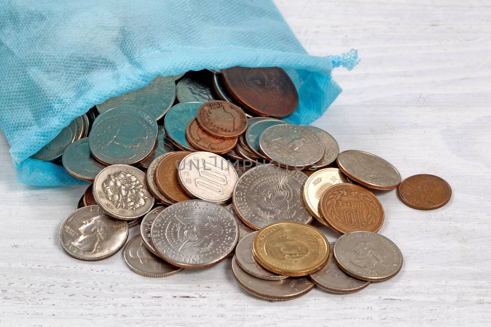 Close up of a bag of money spilling coins onto table. 