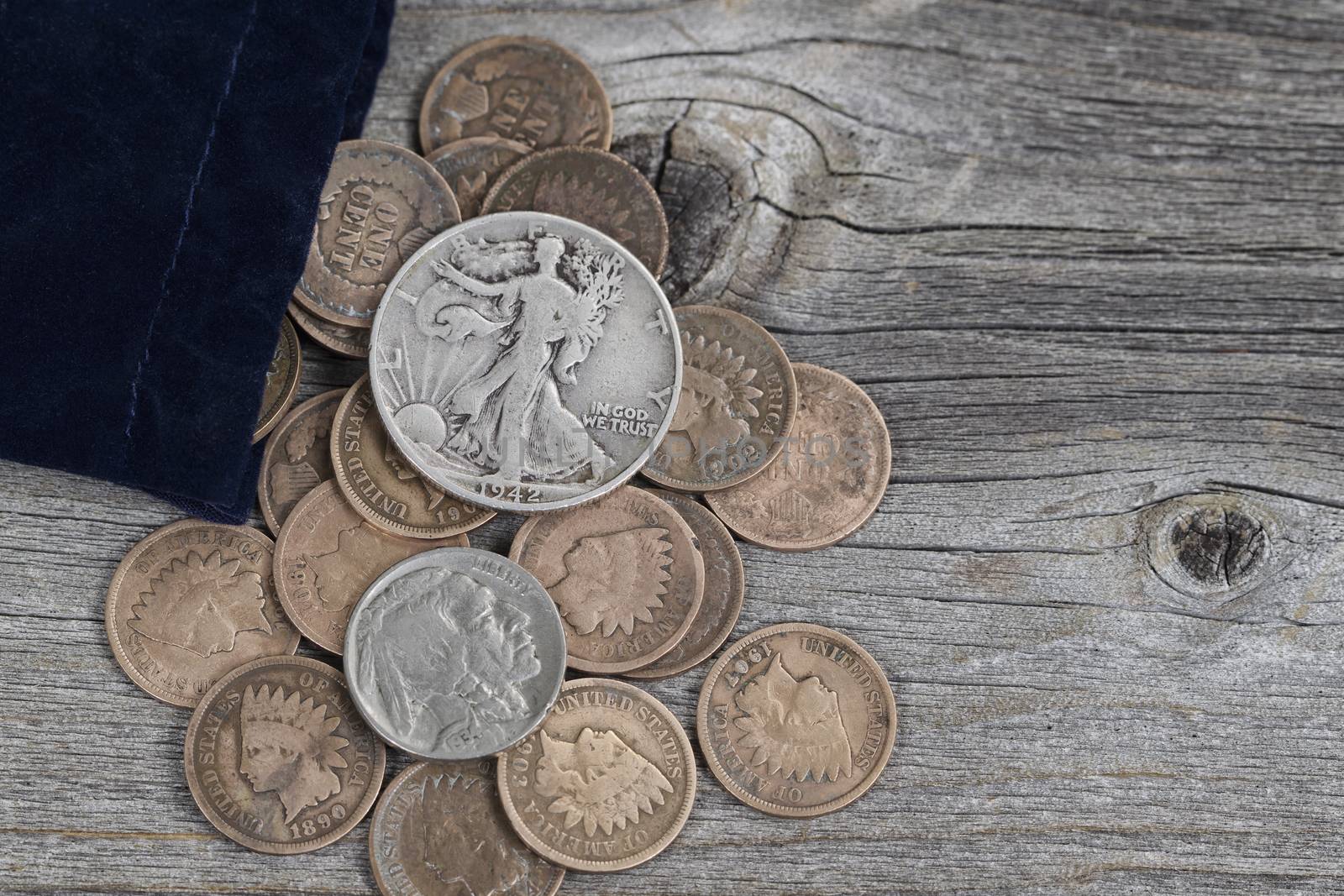 Close up view of a bag of United States vintage coins spilling out onto rustic wood