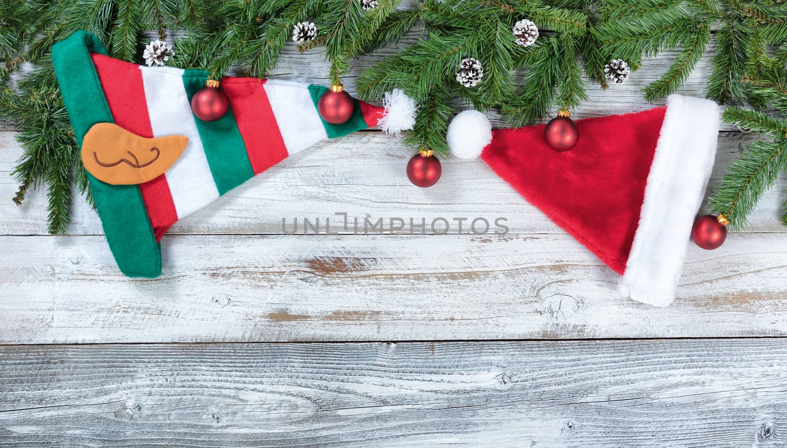 Christmas traditional hat decorations and red ball ornaments on rustic wood in flat lay format