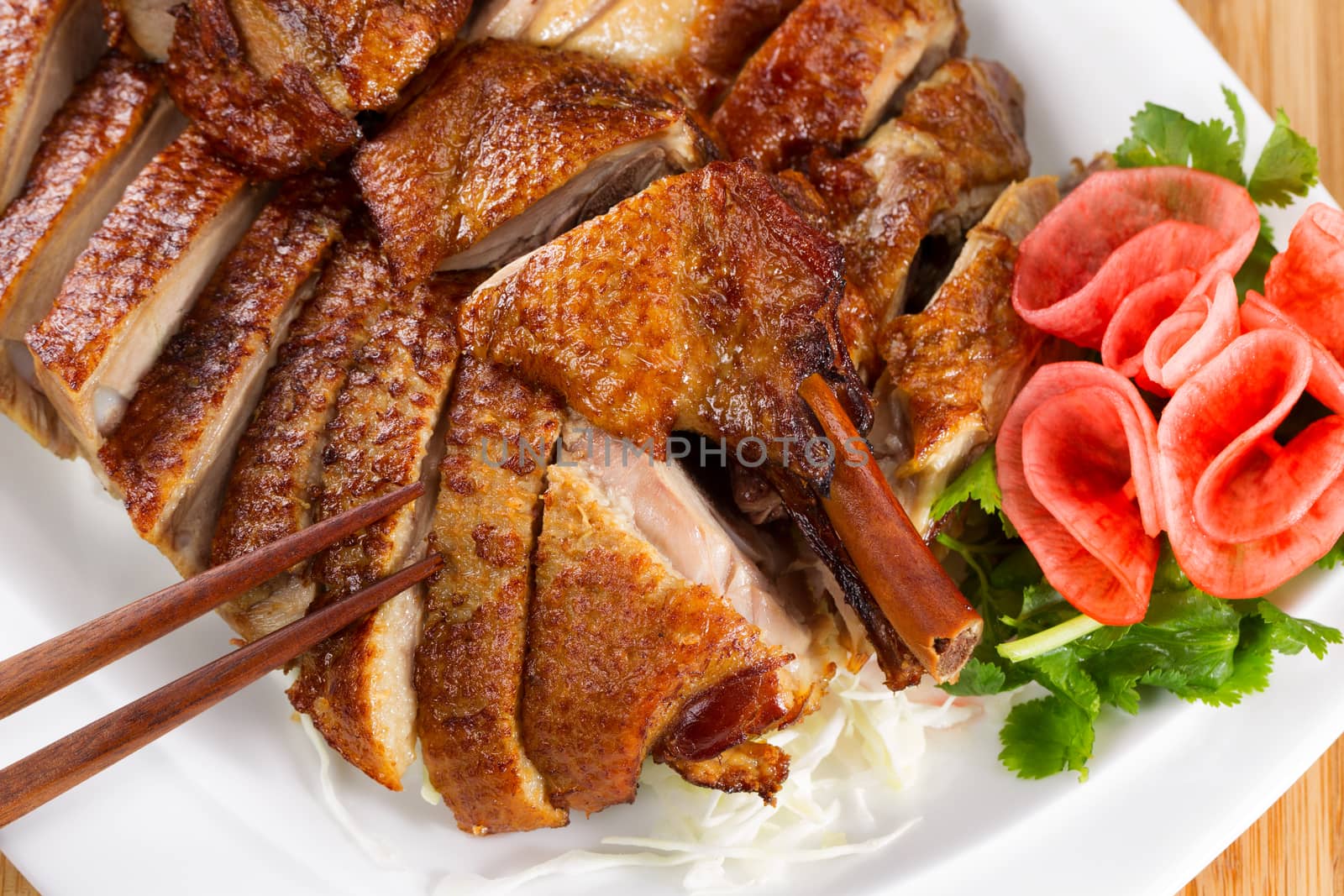 Top view of Chinese crispy roasted duck in white plate with natural bamboo background 