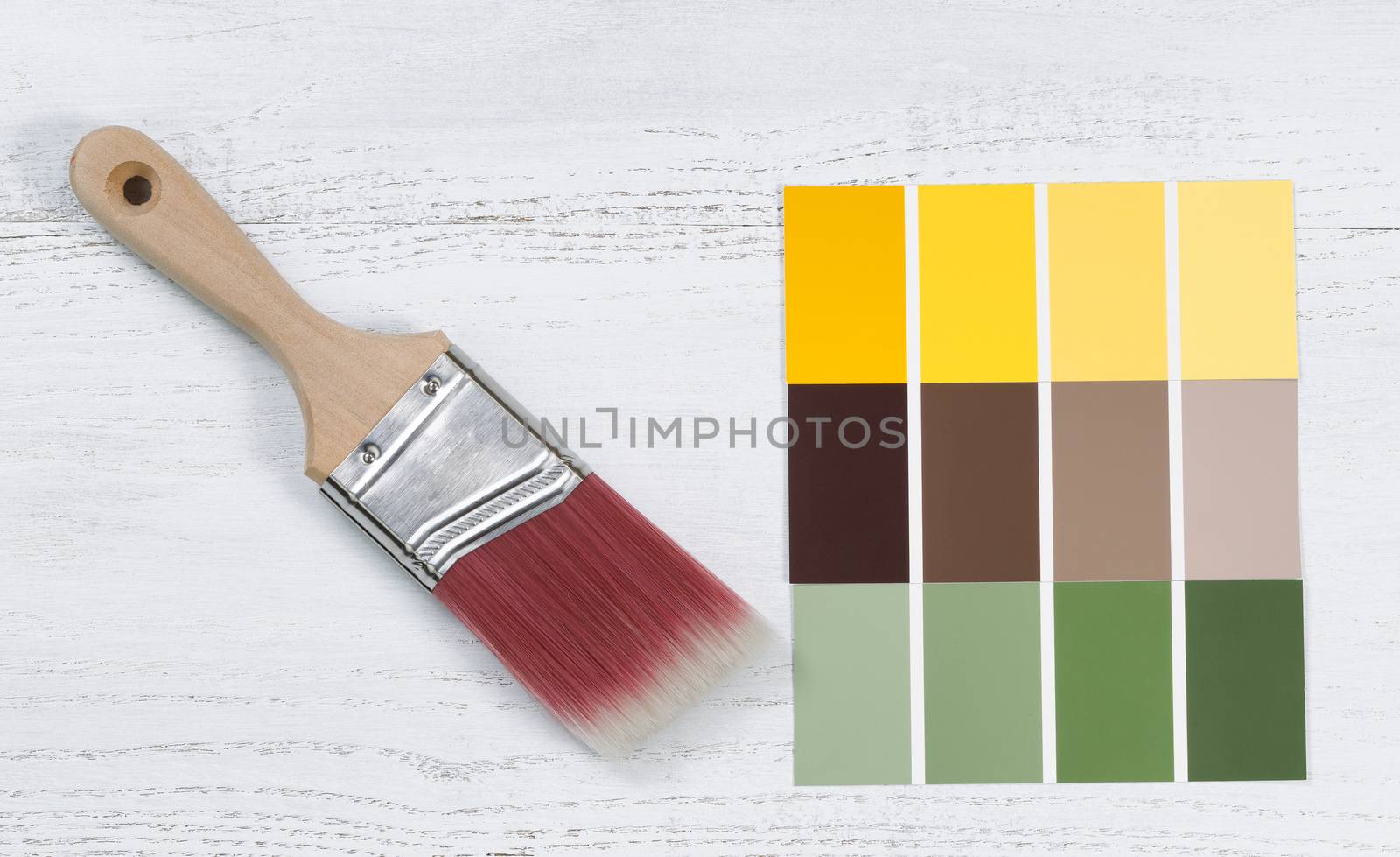 Close up of a new paint brush and paint color choice templates on white wooden boards