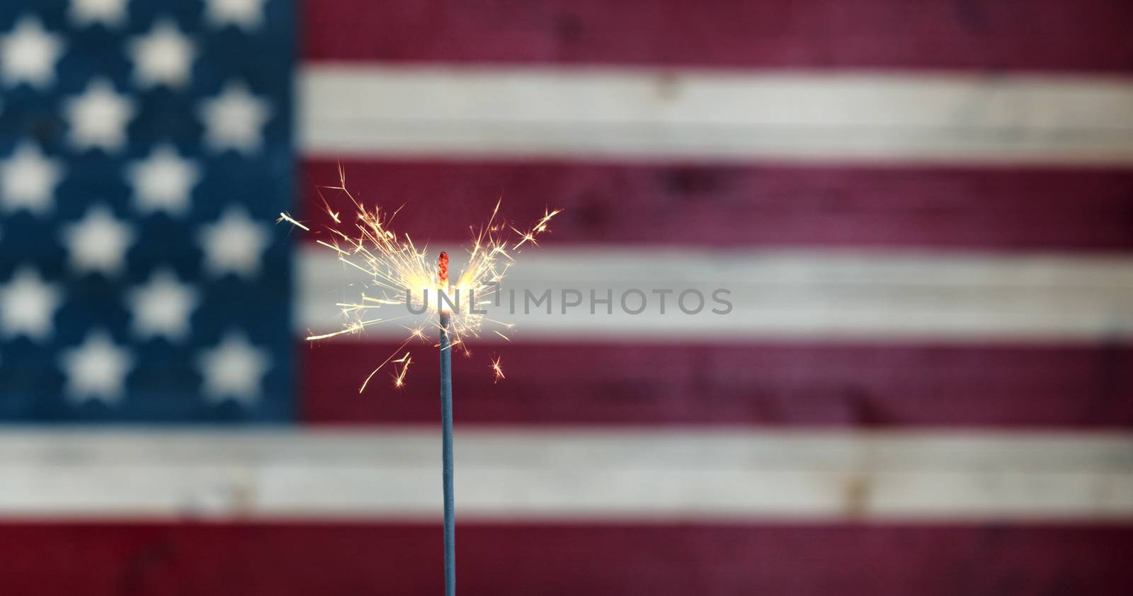 Burning sparkler with rustic wooden United States Flag in background