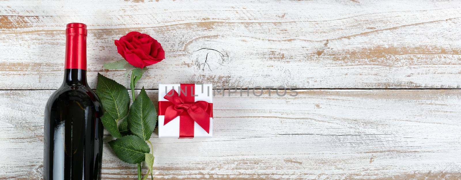 Romantic Valentines Day celebration with red wine and gifts on white rustic wood 
