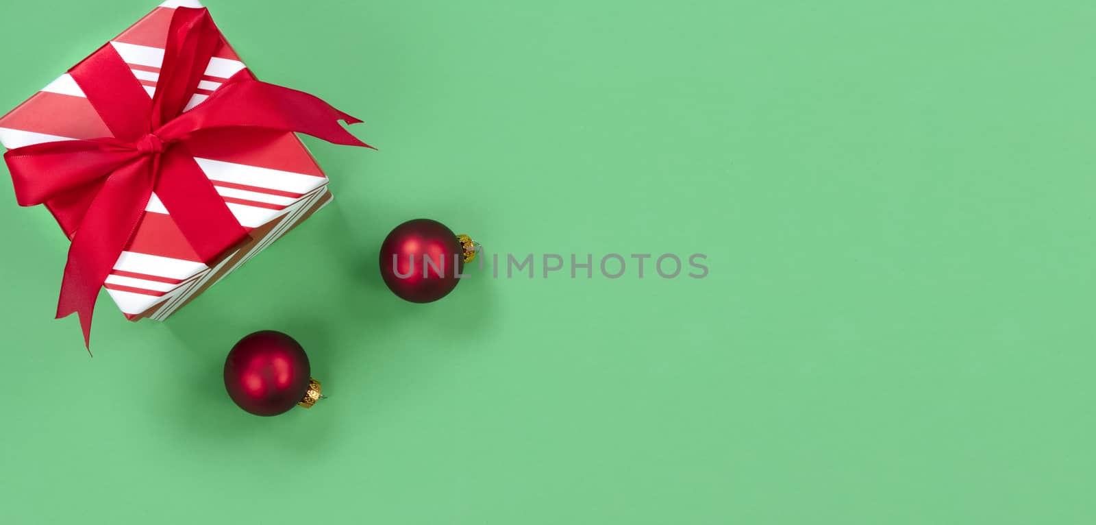 Green background with gift box and red ornaments for the Christmas season 