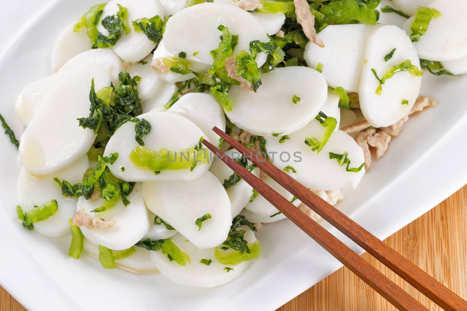 Chinese rice noodles with pork slices in white plate with natural bamboo background 