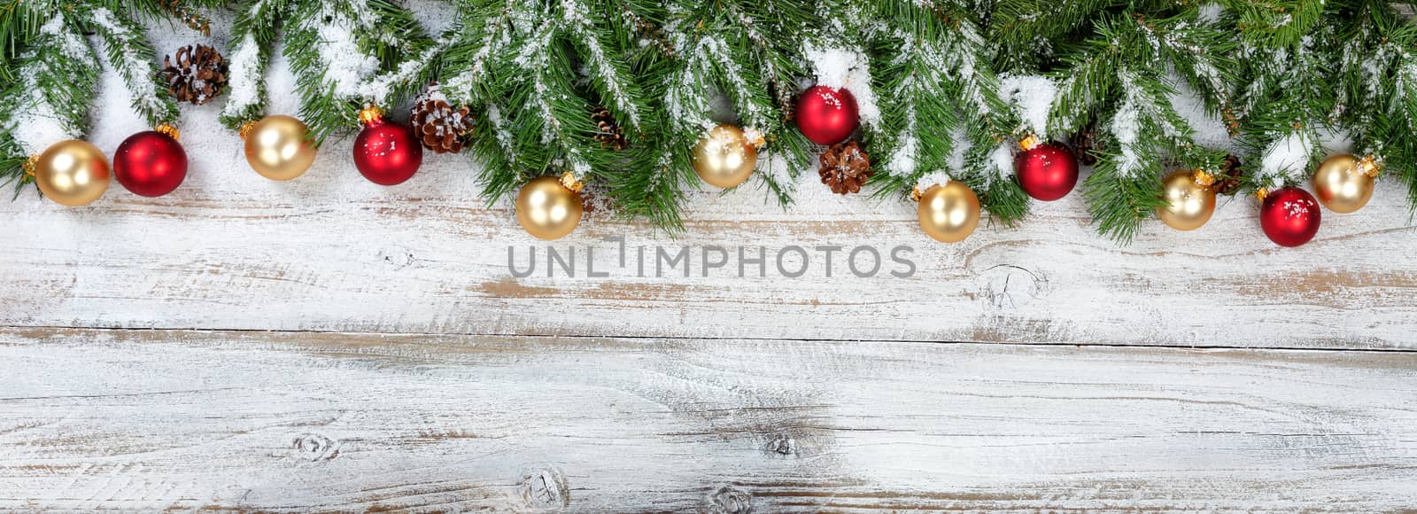 Christmas evergreen branches with golden and red ornaments on rustic white wood background