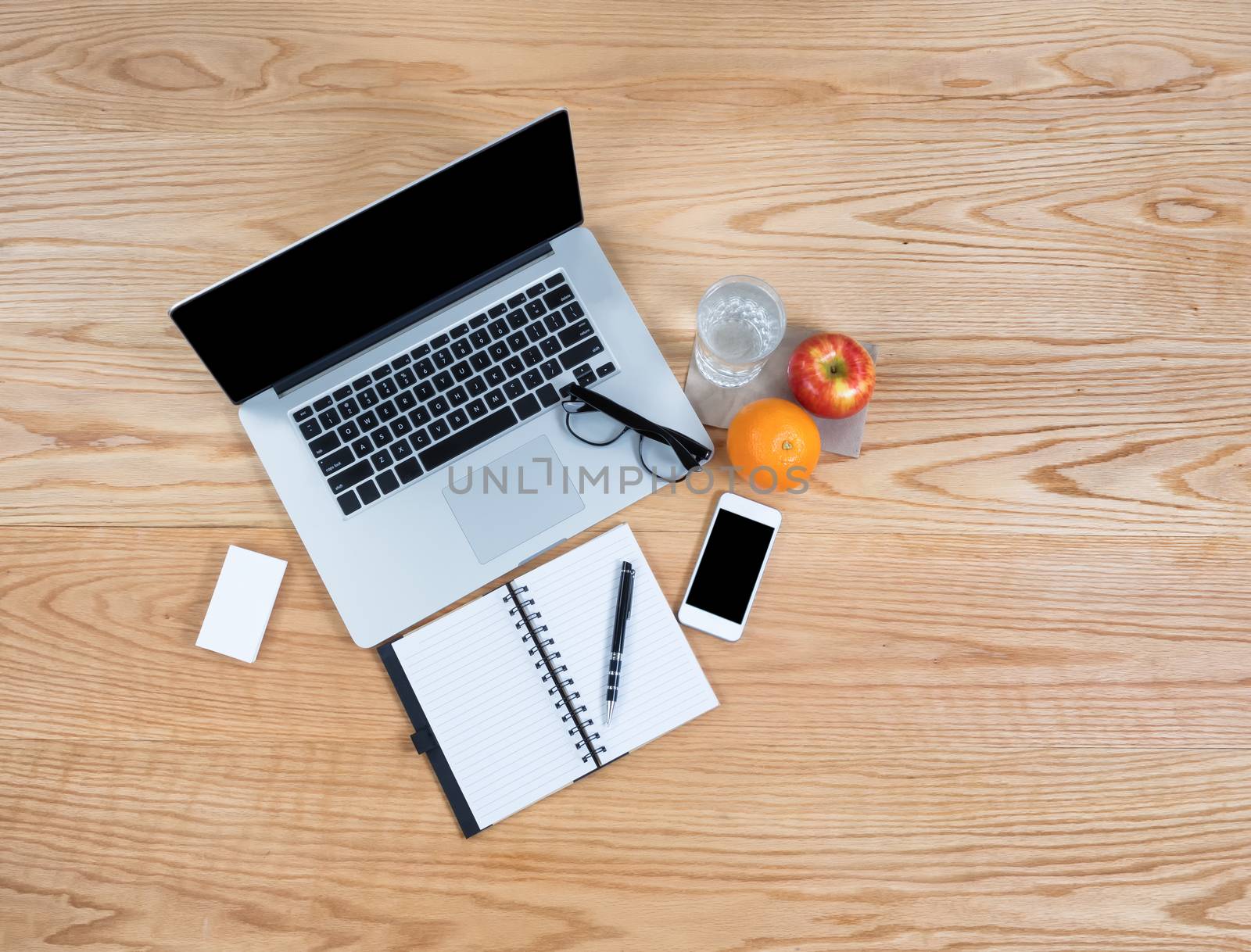 Clean oak wooden desktop with laptop computer, smart phone, water and fresh fruit 