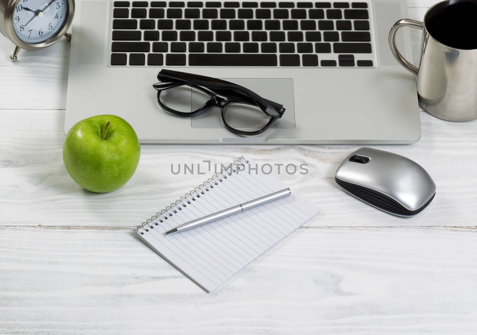 Front view of laptop computer with office work objects and coffee. Layout in horizontal format.