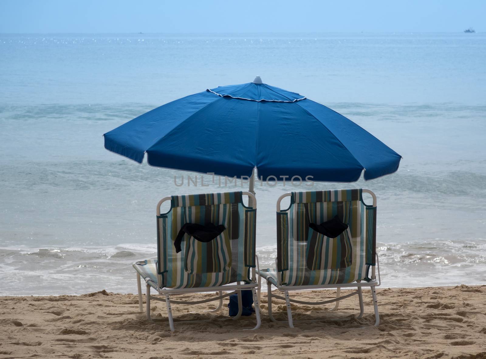 Empty beach chairs with umbrellas on sandy beach of Pacific Ocea by tab1962