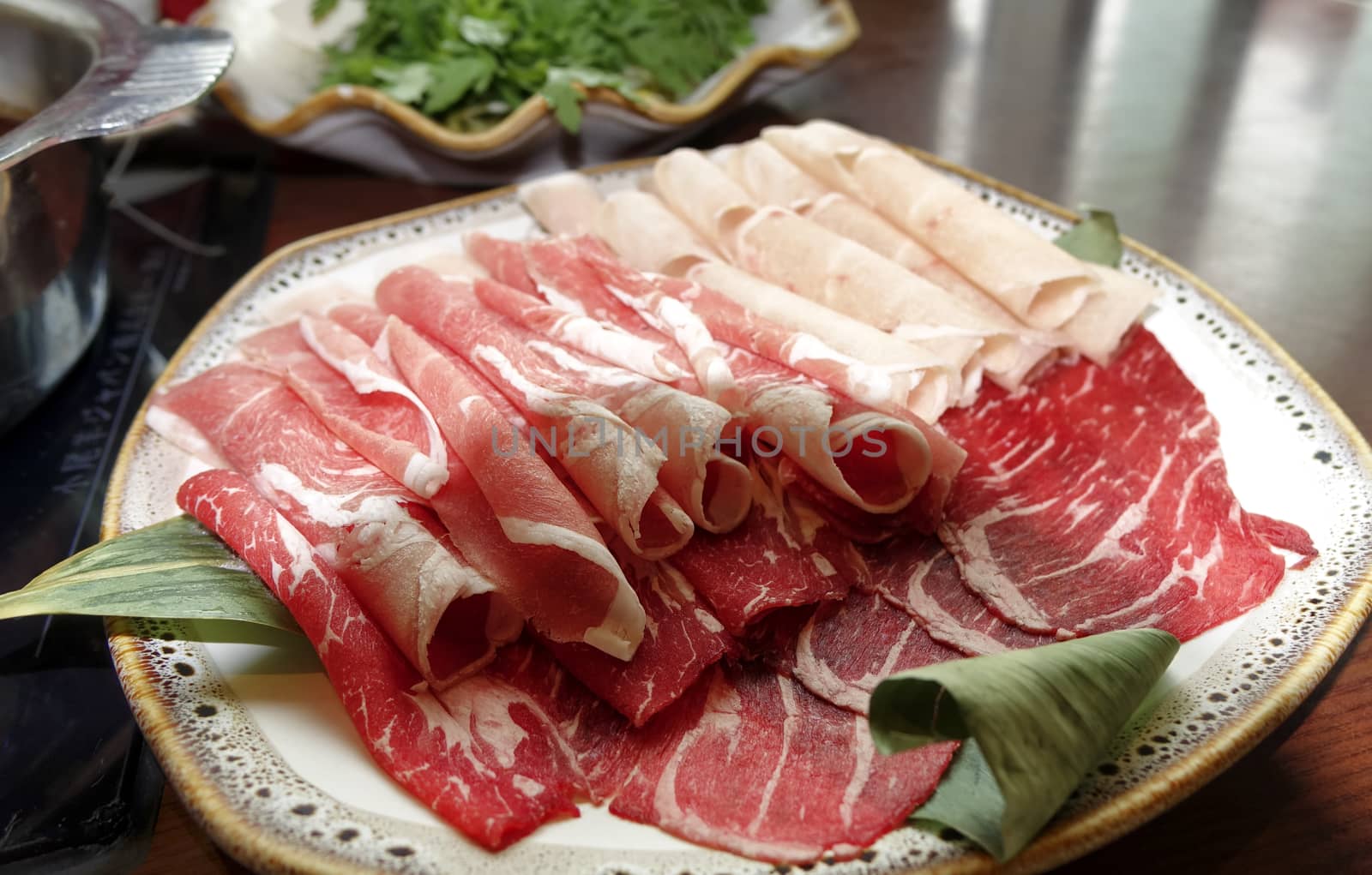 Raw beef finely sliced for cooking on table with hot pot by tab1962