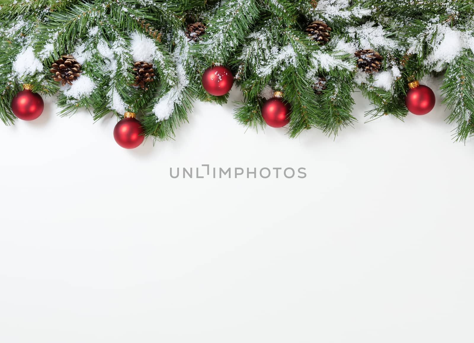 Snowy Christmas red ornaments hanging in fir tree branches  by tab1962