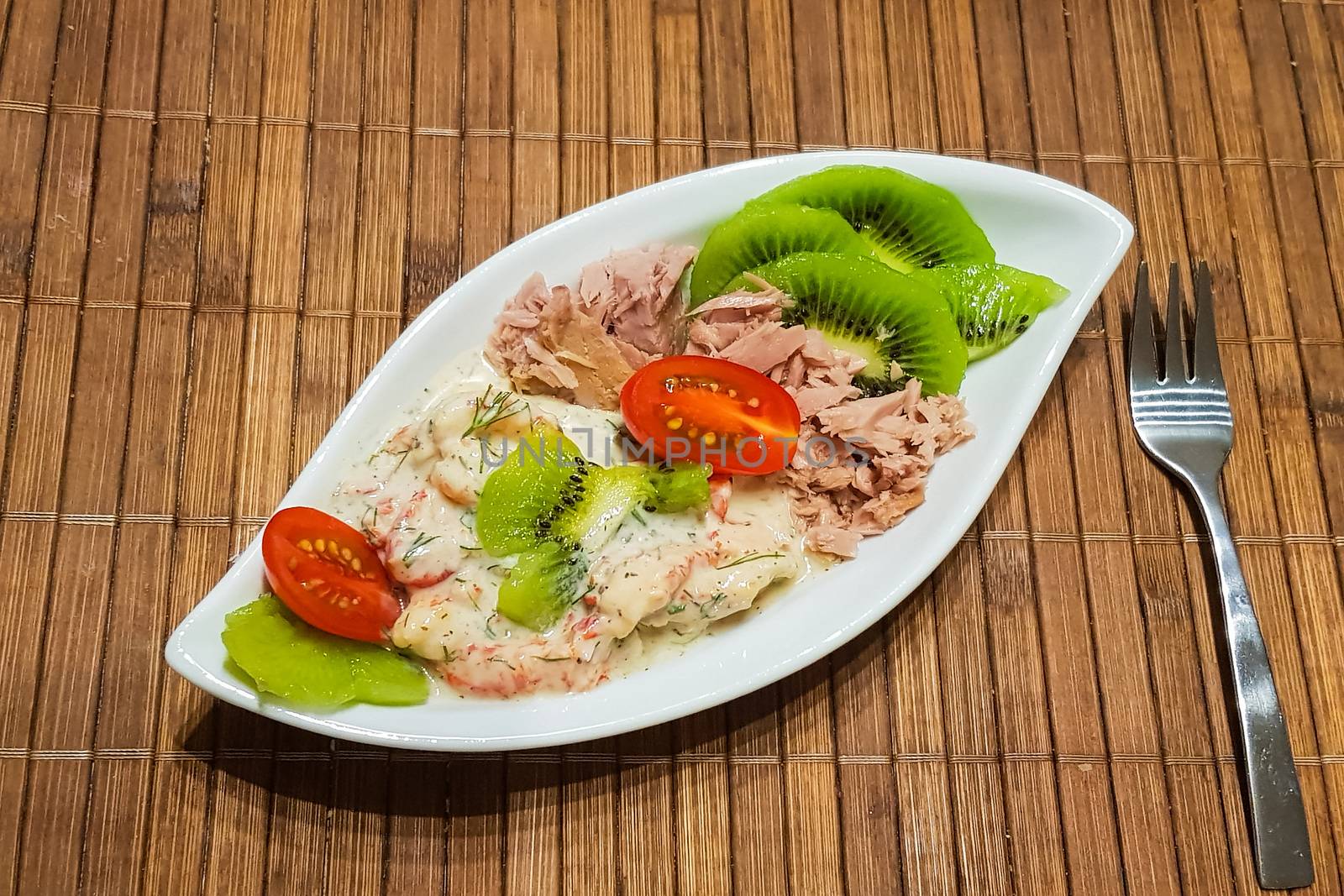 Healthy low-carbohydrate food in small bowl, lunch with tomatoes, tuna, kiwi, shrimp homemade sugar-free sauce.