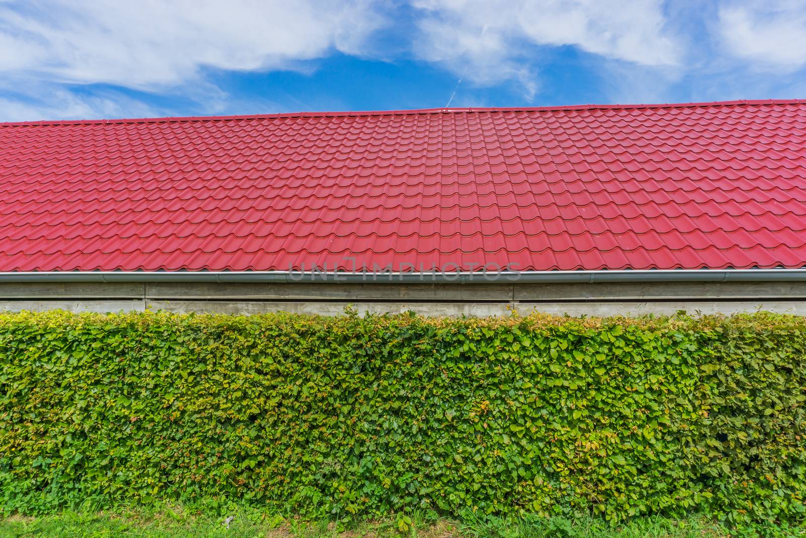 building with red rooftop tiling and hedge