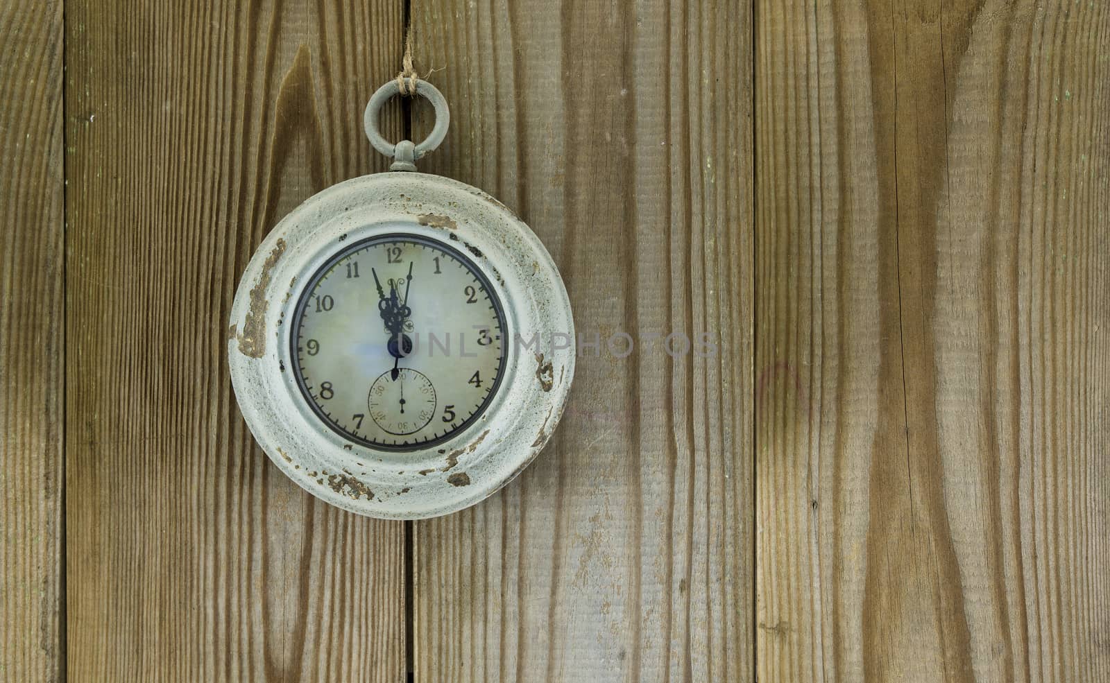 old clock indicates five to twelve on wooden background