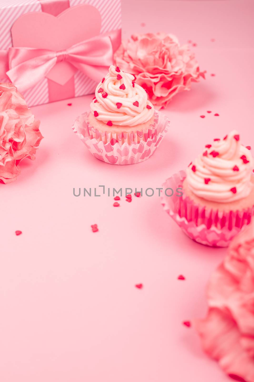 Valentine day love cupcake decorated with cream and hearts rose flowers and gift on pink background with copy space for text