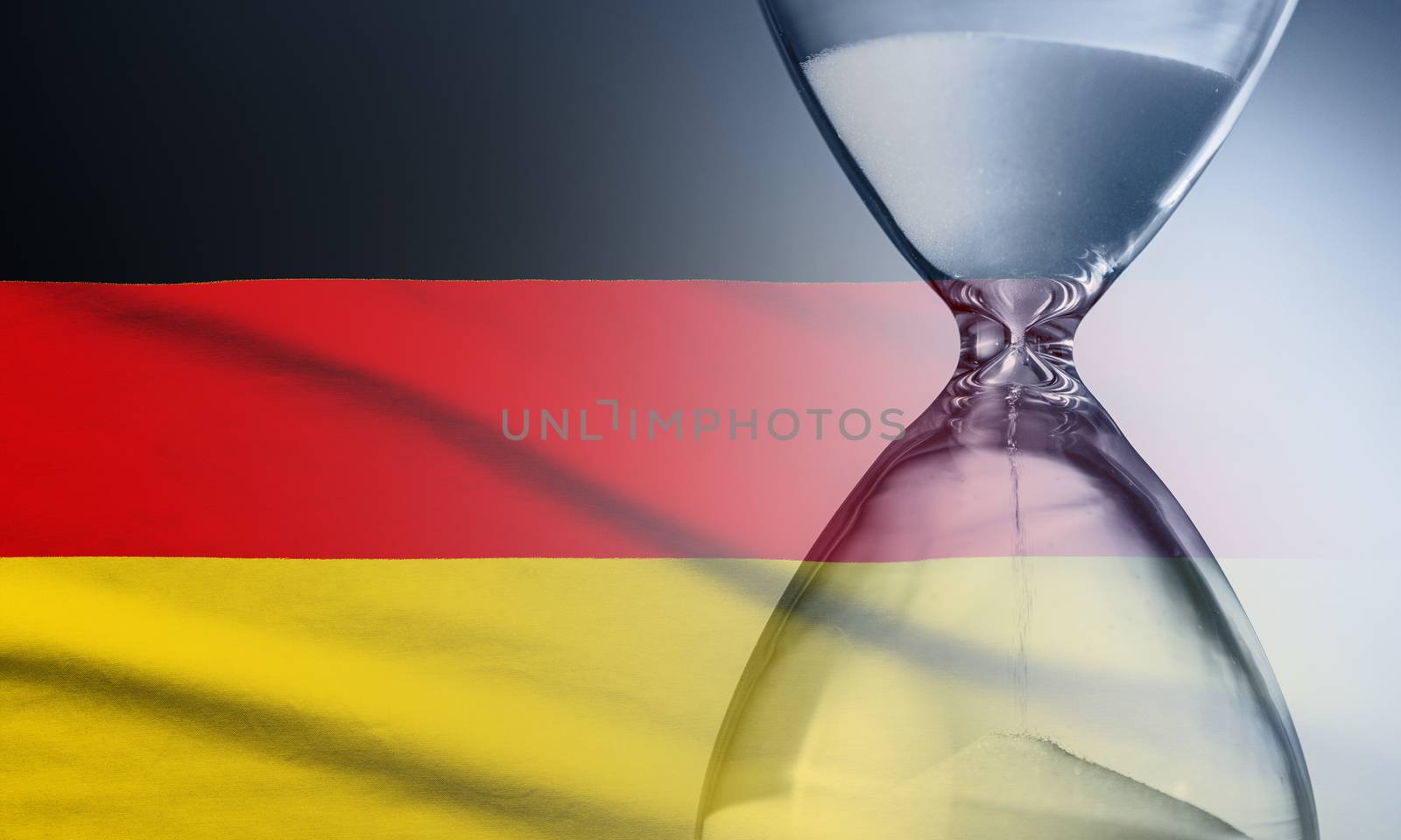 Hourglass with running sand over the flag of the Germany in a concept of urgency, countdown , deadlines and time management