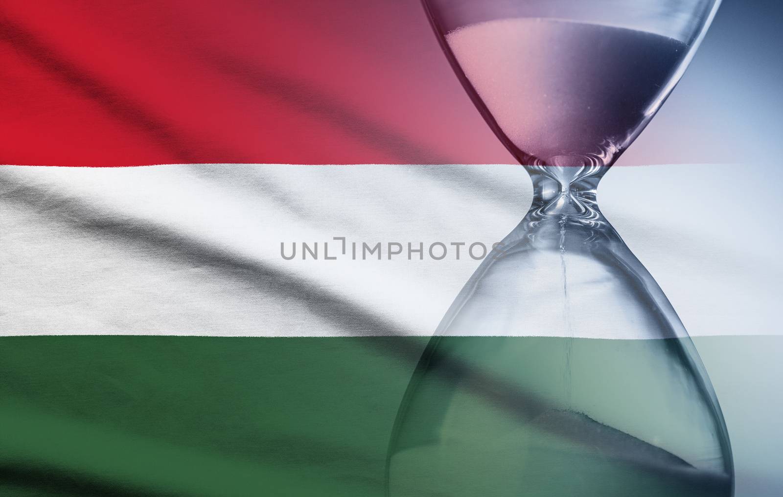 Hourglass with running sand over the flag of the Hungary in a concept of urgency, countdown , deadlines and time management