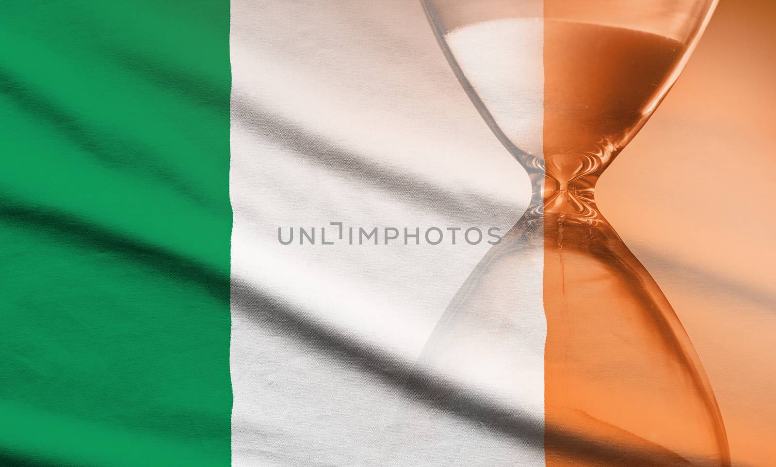 Hourglass with running sand over the flag of the Ireland in a concept of urgency, countdown , deadlines and time management