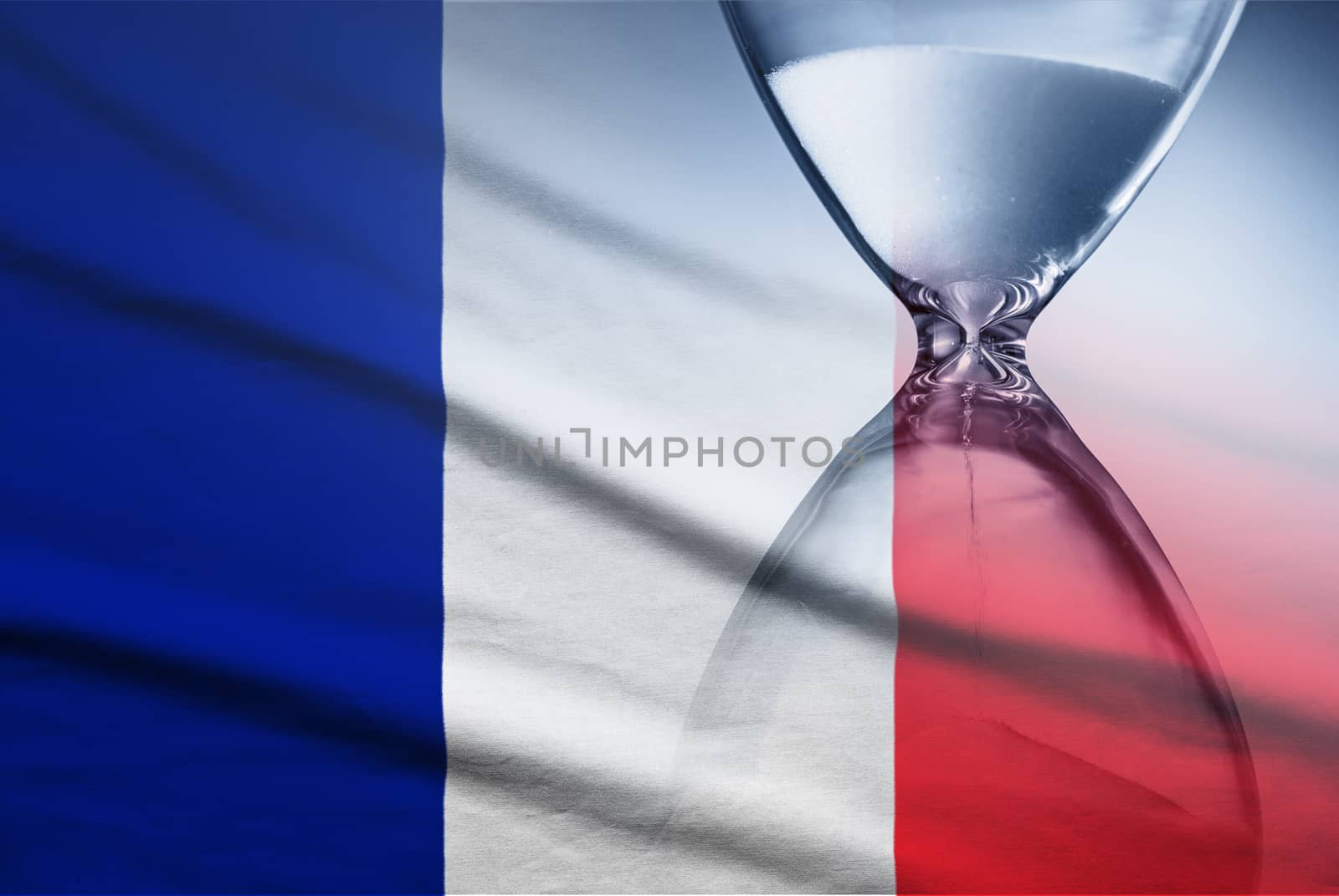 Flag of France with superimposed hourglass with running sand conceptual of deadlines, countdown, passing time, urgency, crisis and time management