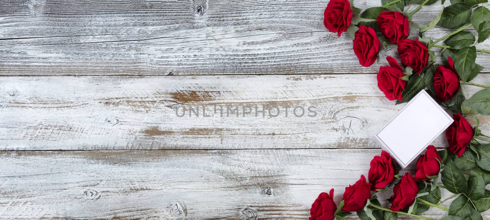 Small gift box with a dozen red roses for Valentines Day on white rustic wood 