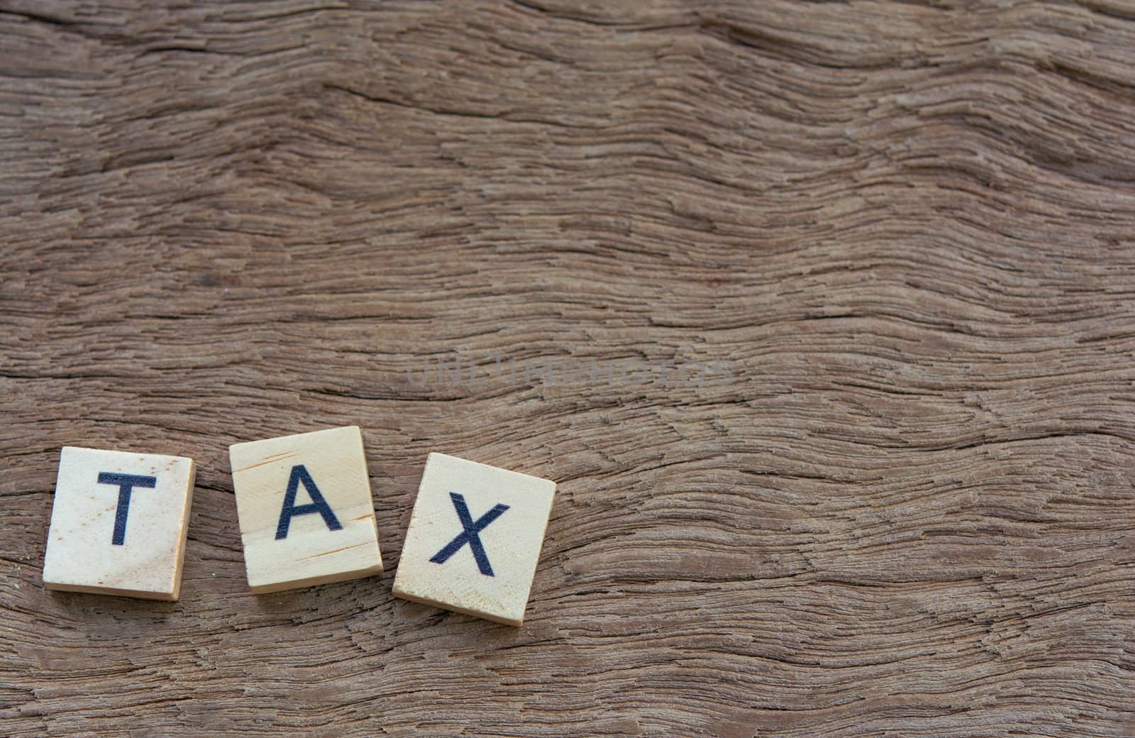 Tax with wooden alphabet blocks, on plank wooden background with copy space
