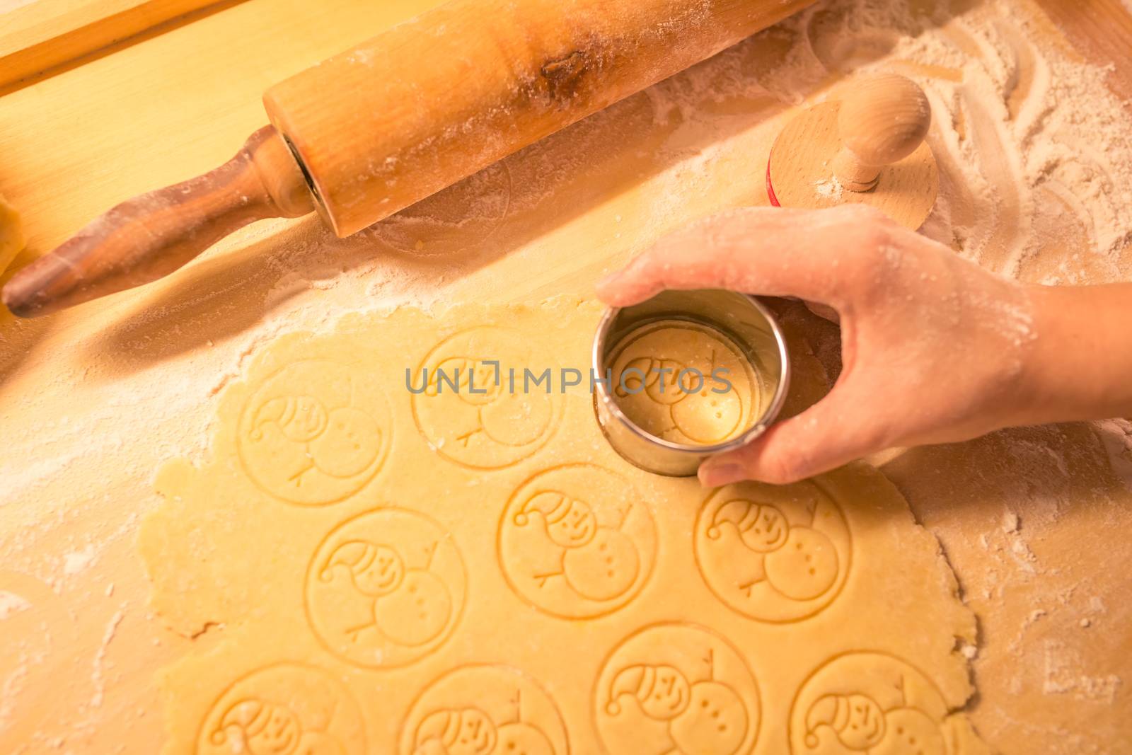 Womans's hand making traditional Christmas cookies. Raw dough and cutter for holiday cookies on the table. Prepare the gingerbread. Snowman dough stamp. by petrsvoboda91