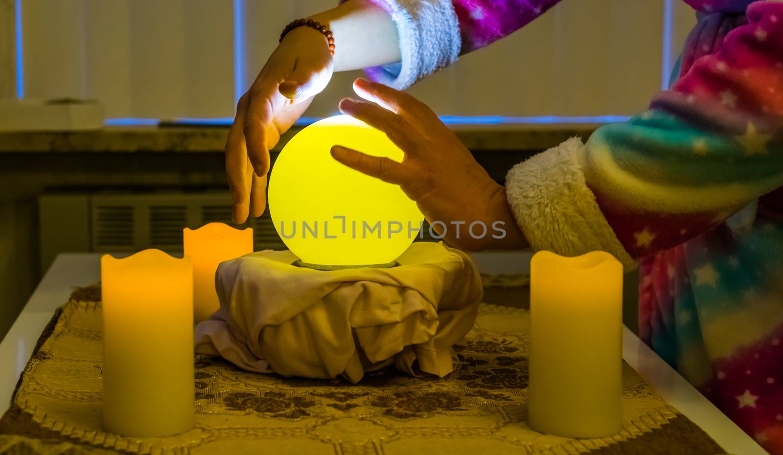 person moving hands around a lighted fortune teller sphere, traditional globe for spirituality and witchcraft by charlottebleijenberg