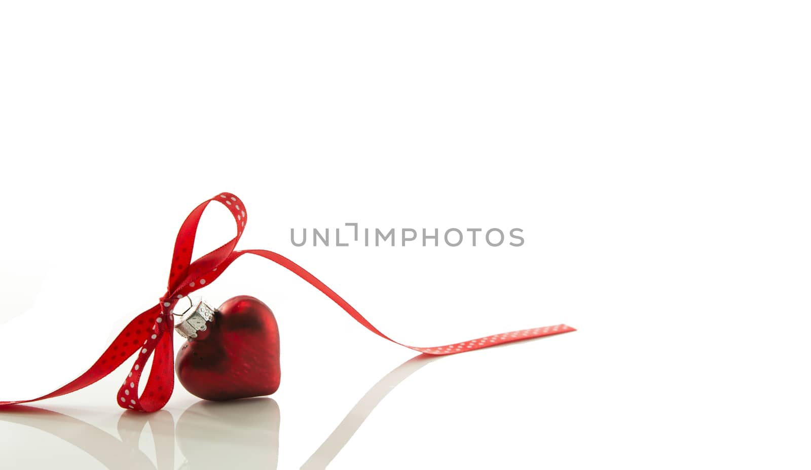 red heart for Christmas with a bow of a red ribbon isolated on white ribbon