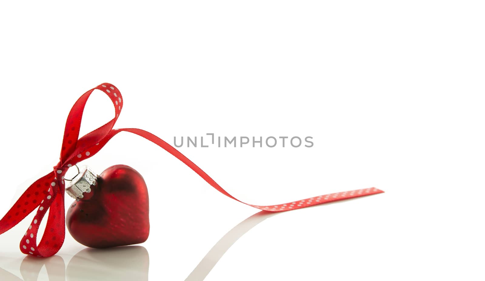 red heart for Christmas with a bow of a red ribbon isolated on white ribbon