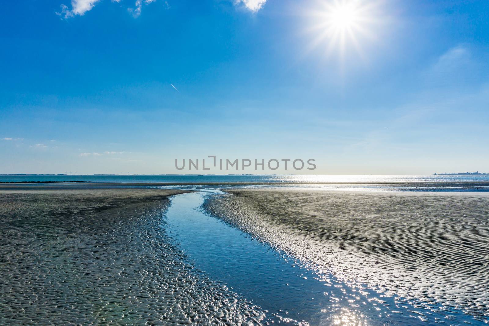 river split from ocean on the beach sunny day by charlottebleijenberg